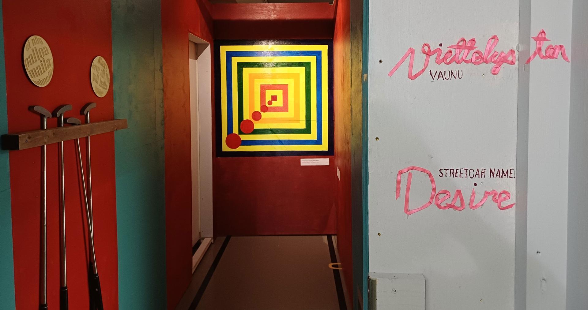 Pakohuoneen käytävällä oleva taideteos, jossa on neliöitä ja ympyröitä.