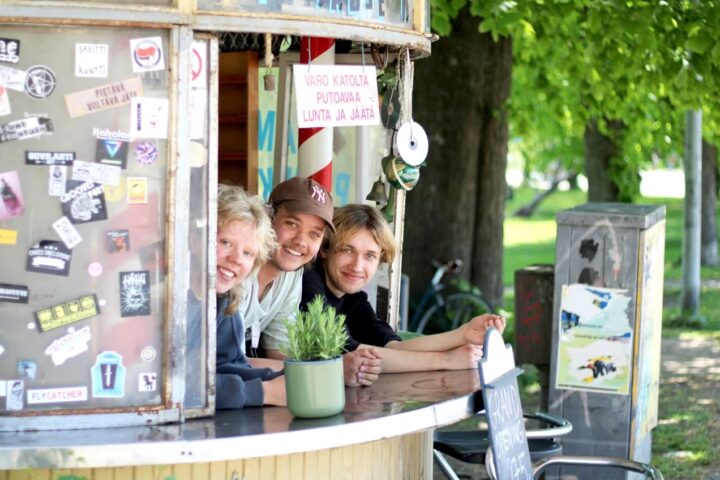 Three friends smiling at a kiosk in Käpylä