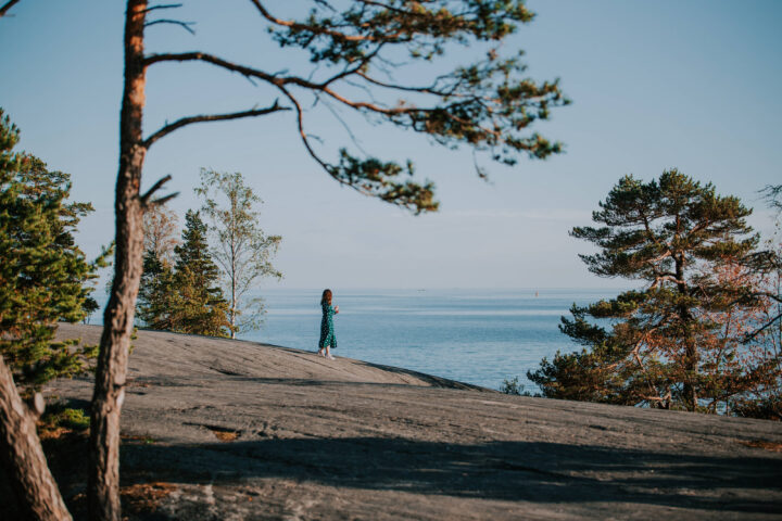 A woman in green dress standing by the shore in Pihlajasaari island in Helsinki