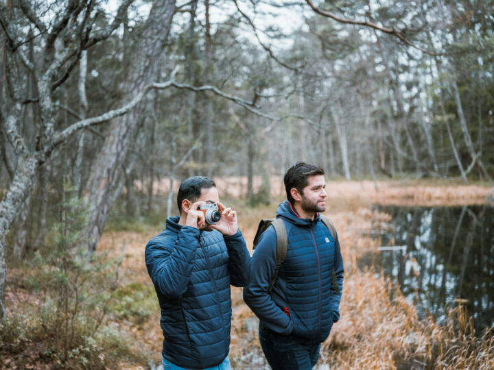 Two men walking by a pond. One man taking a photo