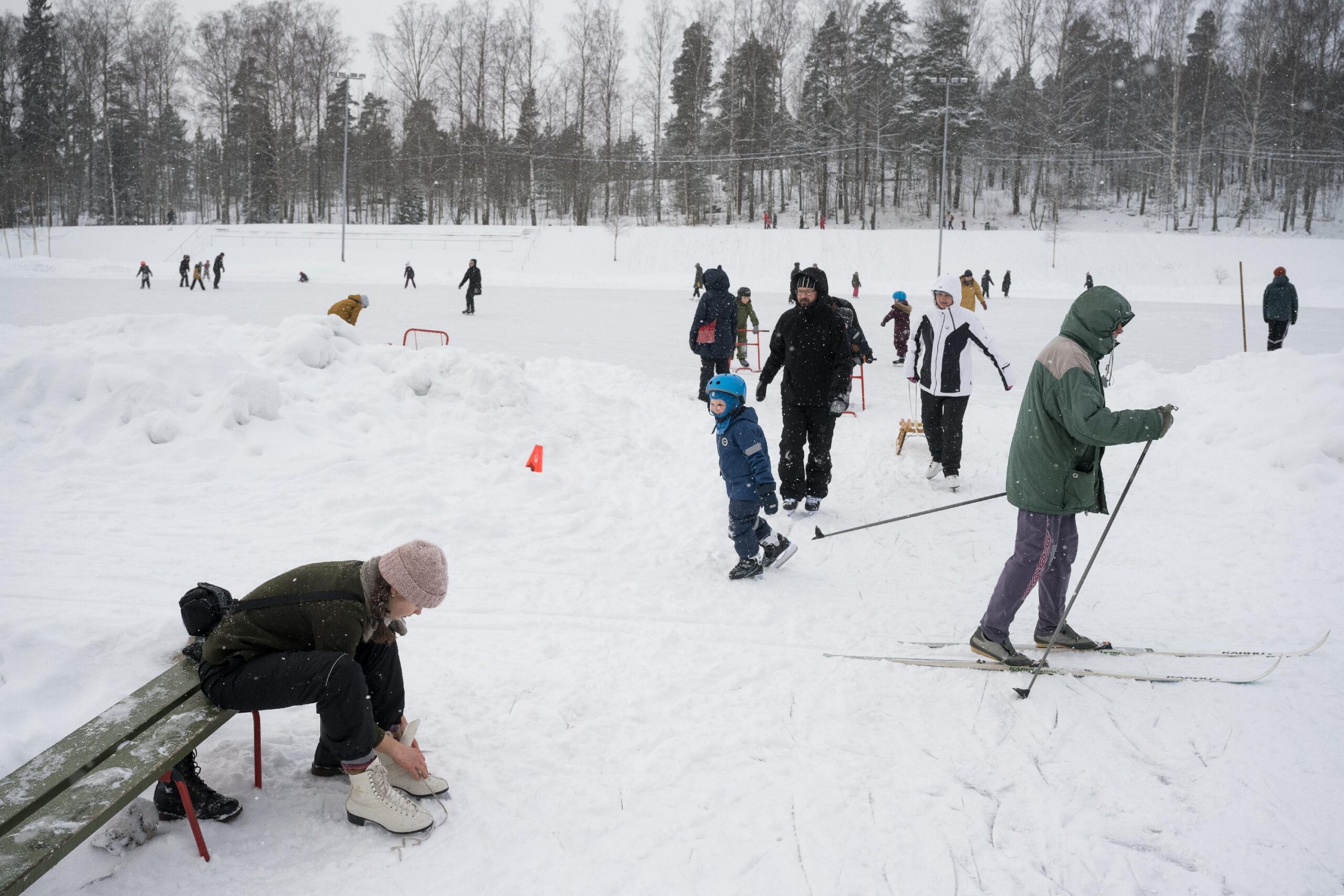 People skiing and skating in the snow in Herttoniemi sports park in Helsinki, Finland.