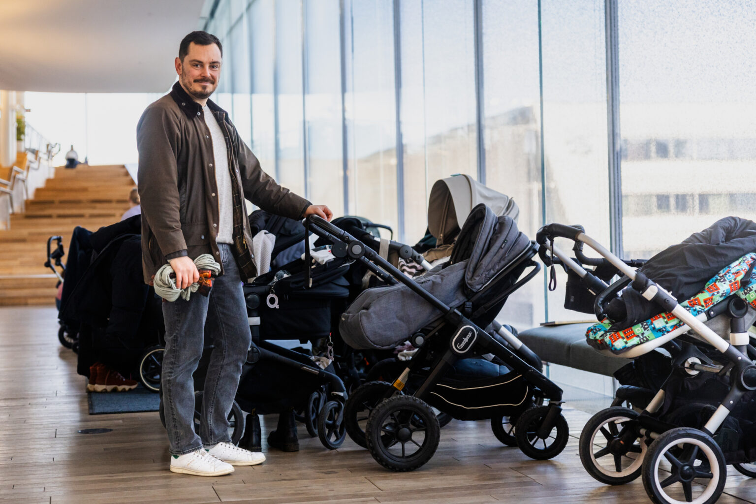 Man standing next to multiple strollers in a modern building