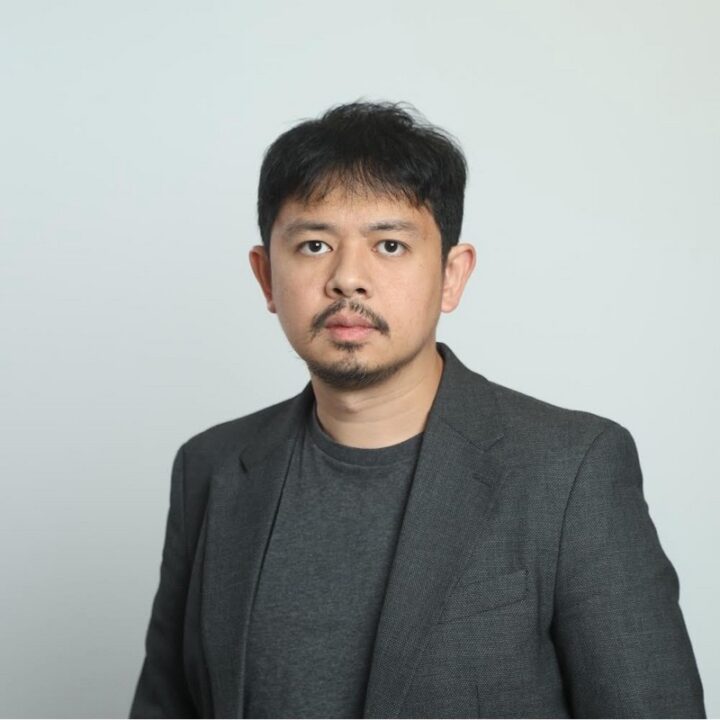 Man in a grey blazer and t-shirt looking at the camera