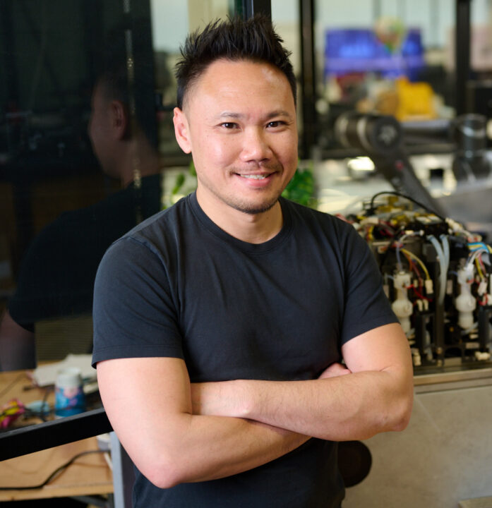 Man with arms crossed in front of robotic equipment