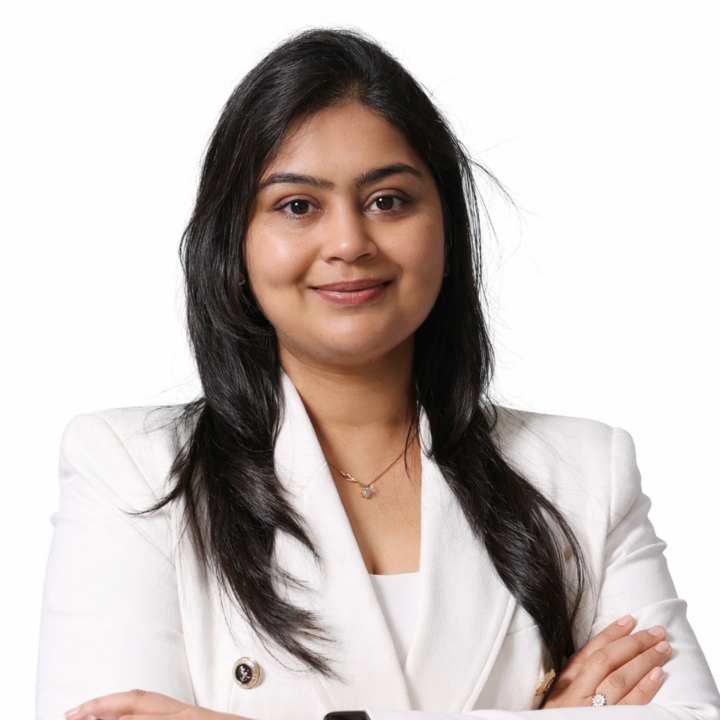 Professional woman in a white blazer, arms crossed, smiling confidently.