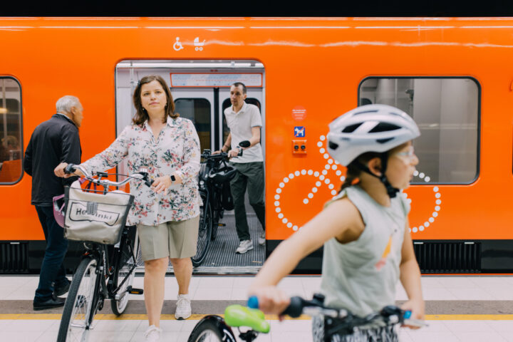 People with bicycles boarding a bright orange Helsinki metro train
