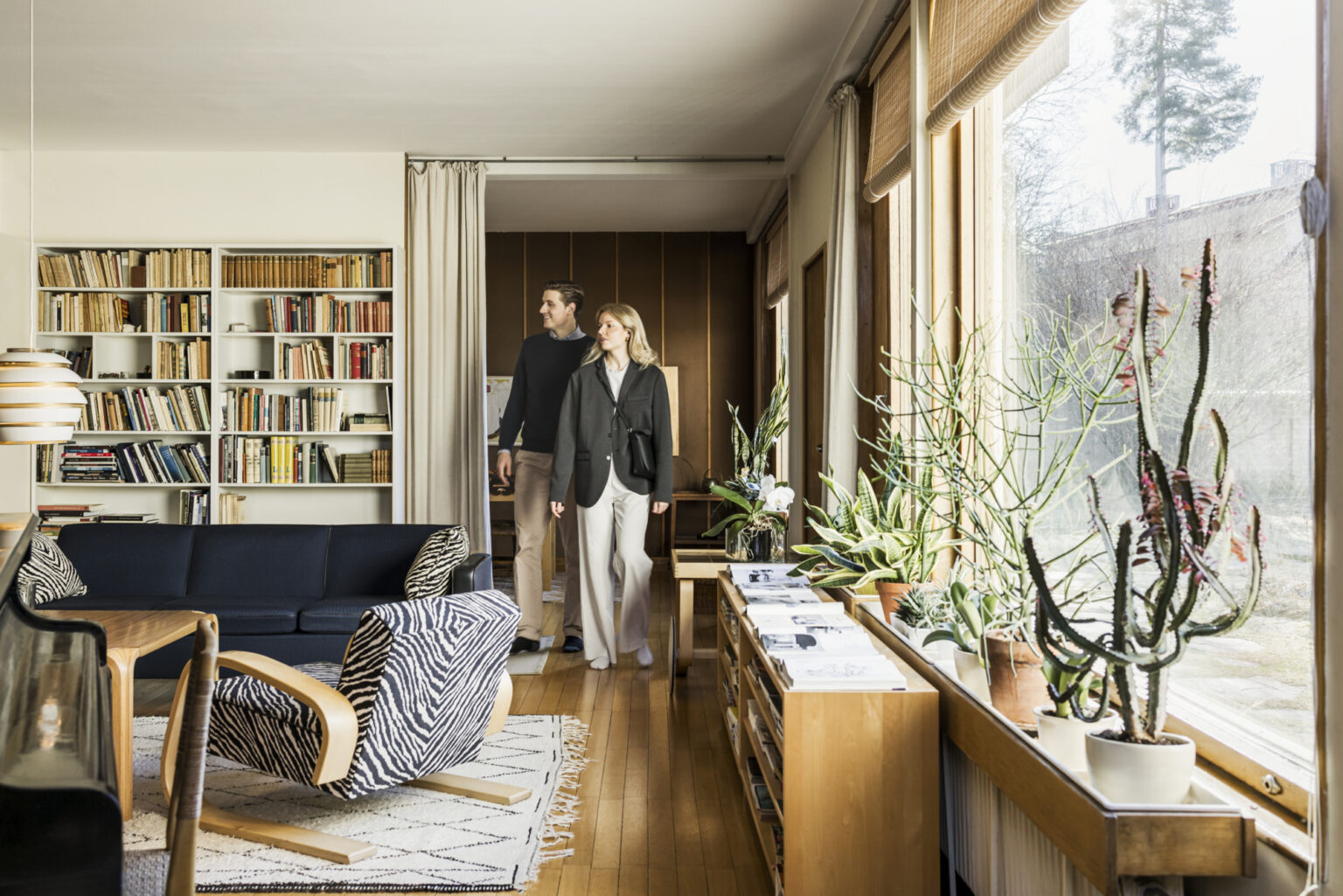 Couple in modern living room with bookshelves and plants