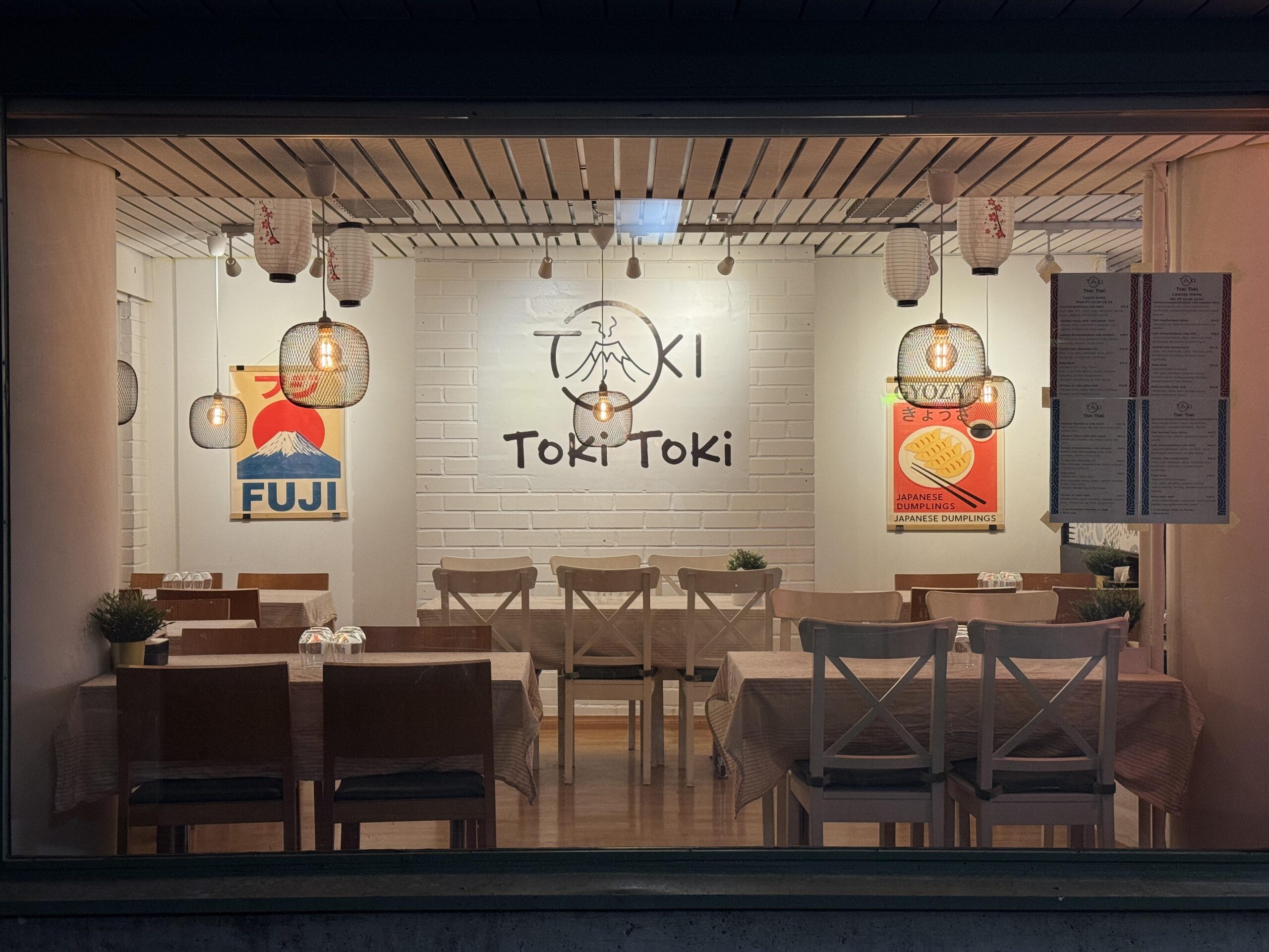 Toki Toki, photographed from the inside.The picture shows the restaurant’s dining area with tables and chairs. The restaurant’s name is written on the wall.