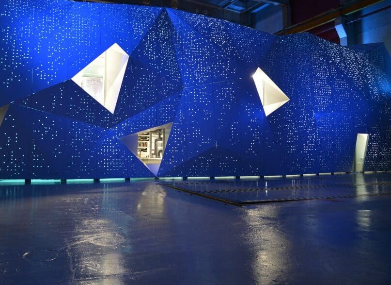 Futuristic blue geometric structure with illuminated panels and triangular openings.