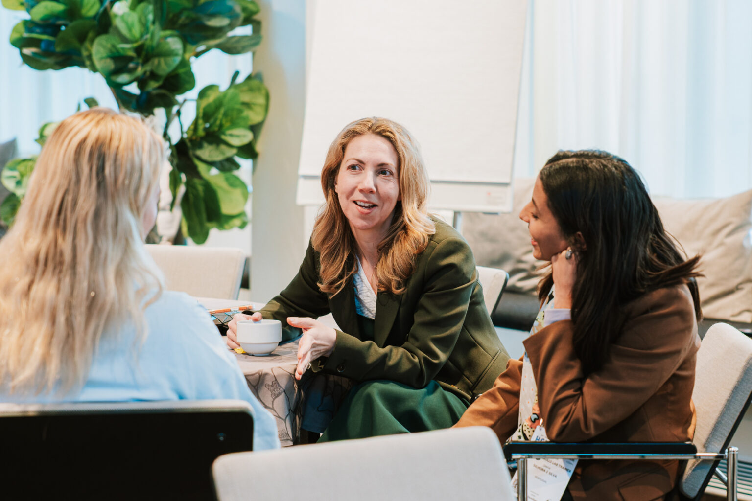 Three women in business attire in a meeting, discussing ideas.