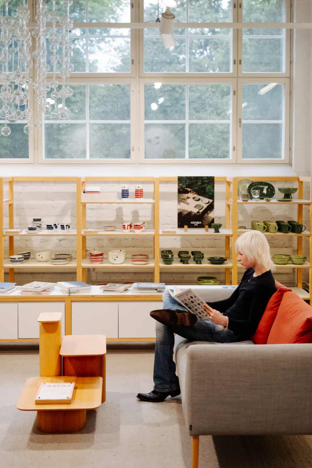 Woman reading in a store with shelving displays of tableware and decor
