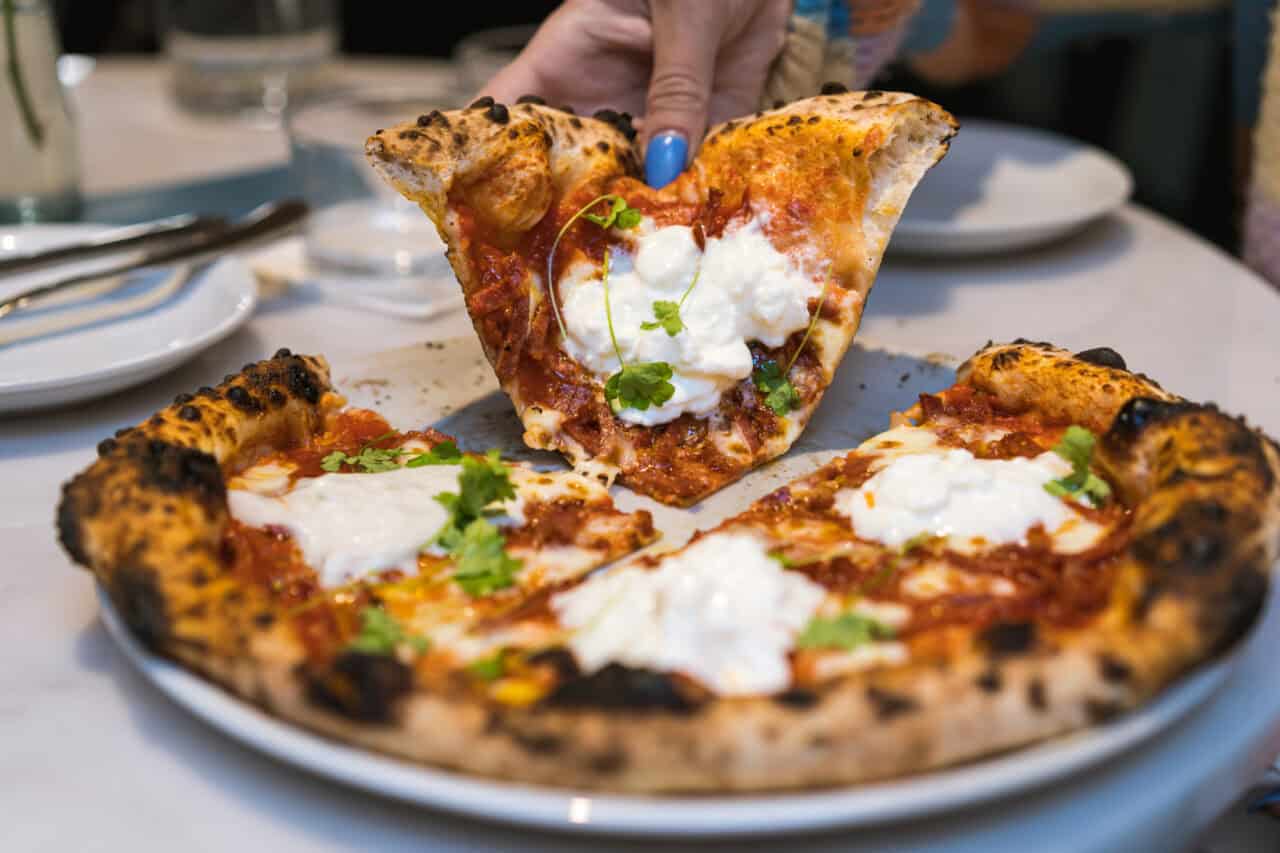Woman eating pizza at restaurant Forza